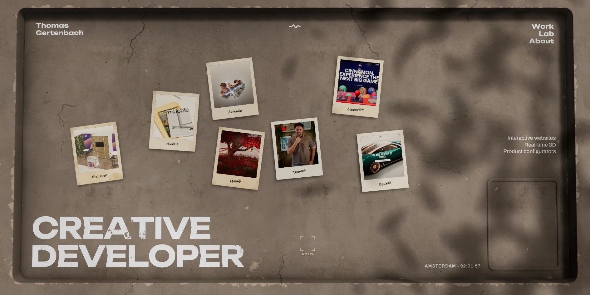 The plaster table on the home page with seven polaroids scattered across it, the two lines CREATIVE DEVELOPER at the bottom left, an empty square recess at the bottom right and leaf shadows falling across the upper right