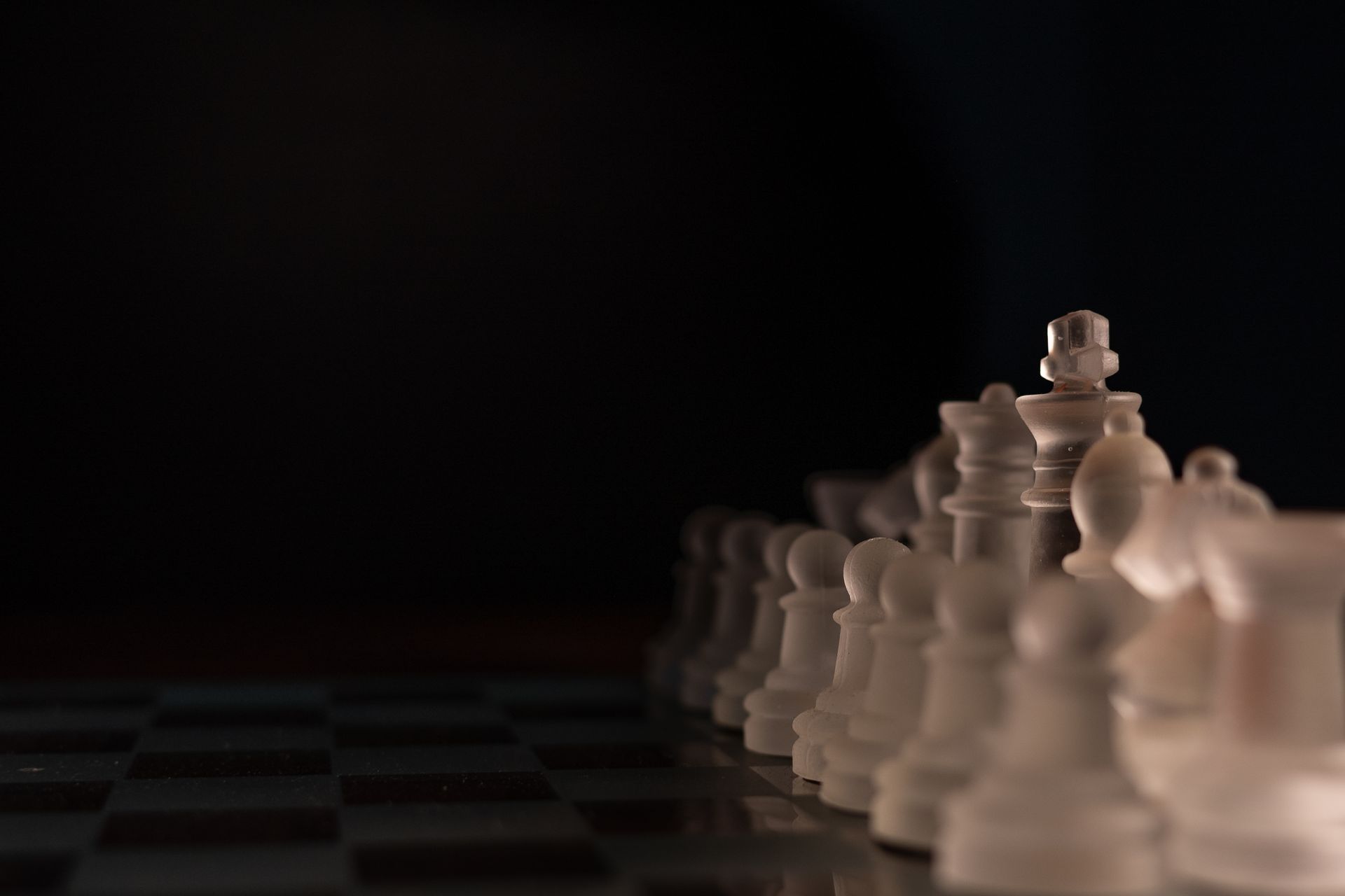 Frosted glass chess pieces lined up on a board in cool dramatic light — strategy and ranking